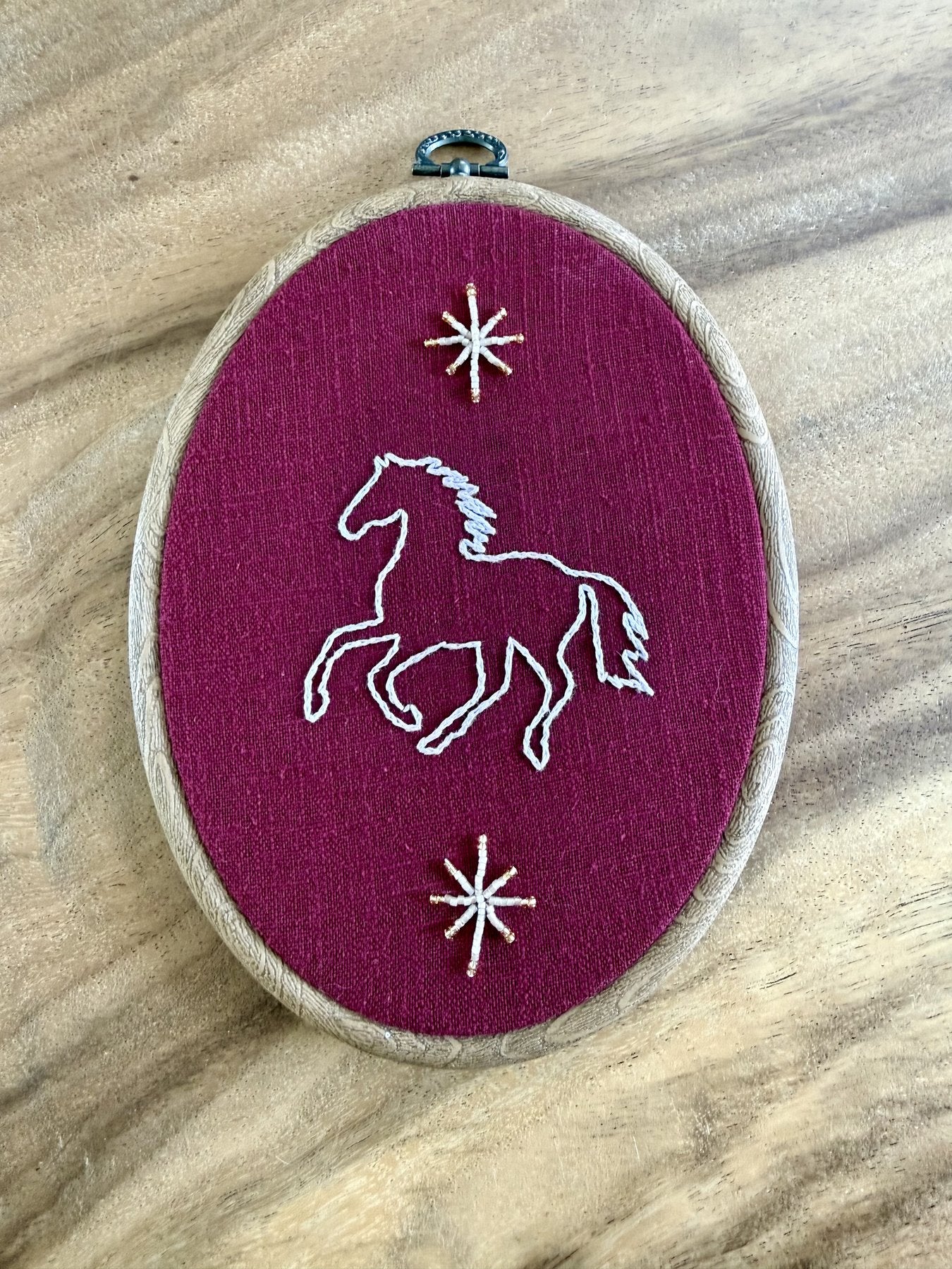 Handgeborduurde paard met sterren op bordeaux linnen in ovale houten borduurring, Amber Nicola