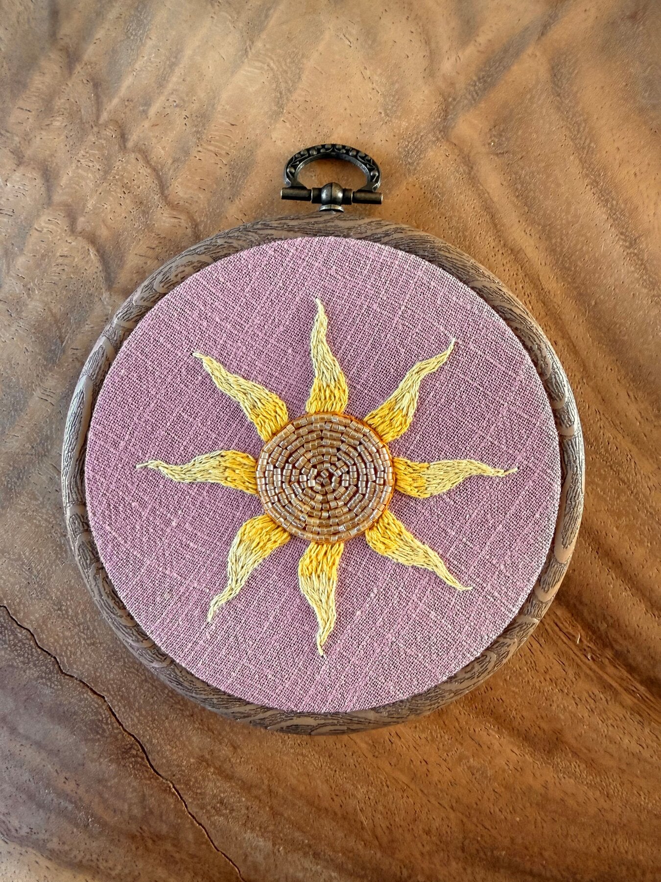 Handgeborduurde zon wandhanger op lila linnen in houtlook borduurring, gemaakt door Amber Nicola