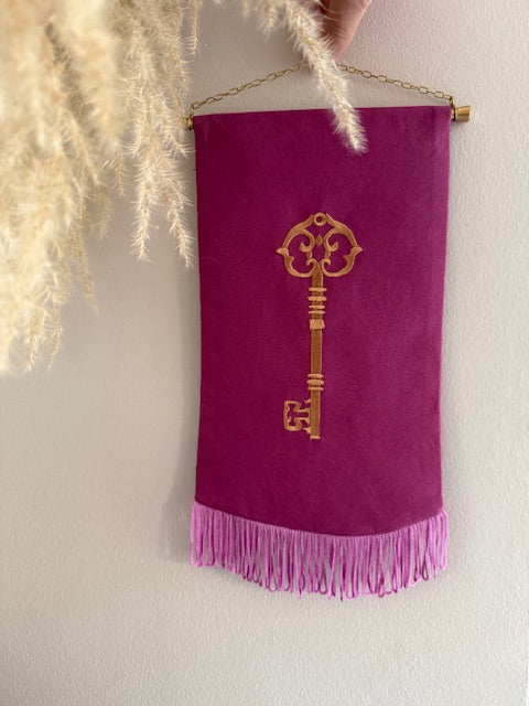 Wandhanger met machinaal geborduurd antiek sleutelmotief in fuchsia met franje randje — Amber Nicola
