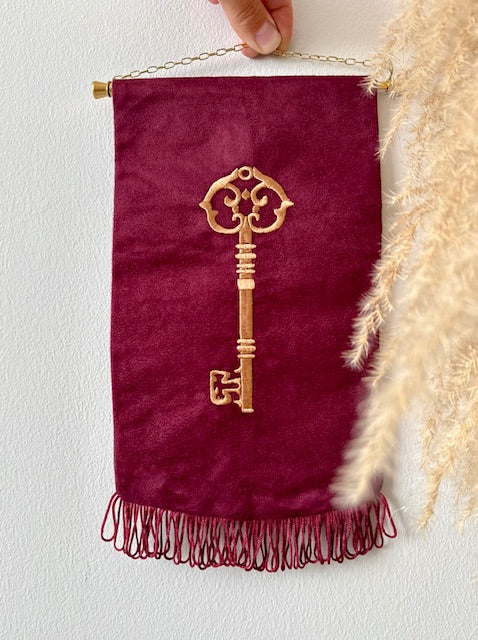 Wandhanger met machinaal geborduurd antiek sleutelmotief op suedine in bordeaux rood — Amber Nicola