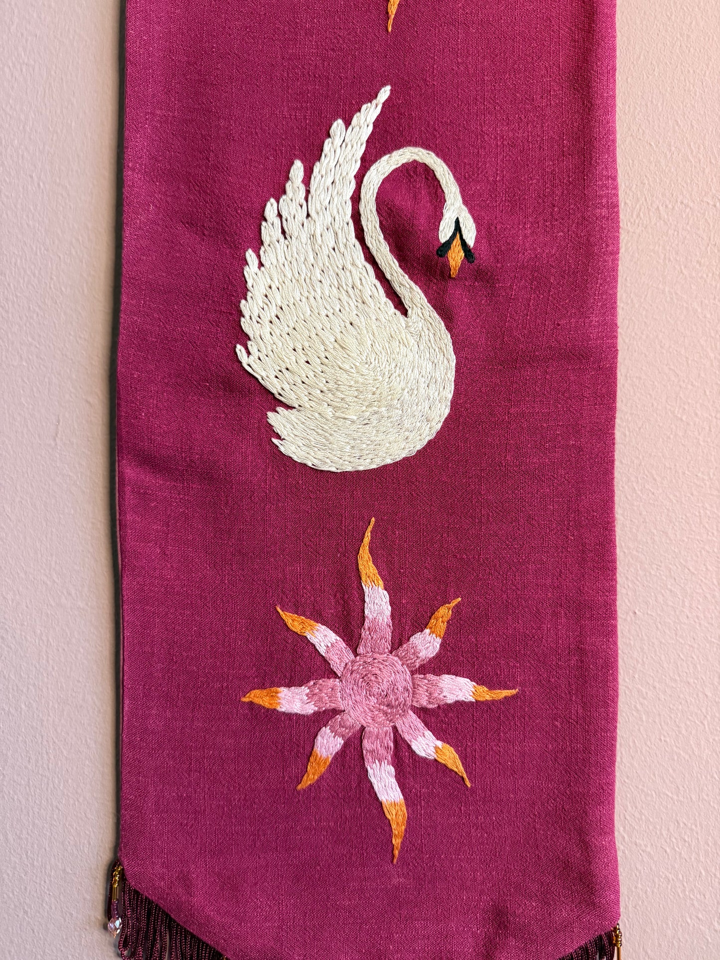 Detail van handgeborduurde wandhanger Aurora Swan met zwaanmotief, kralen en franjerand op linnen — Amber Nicola
