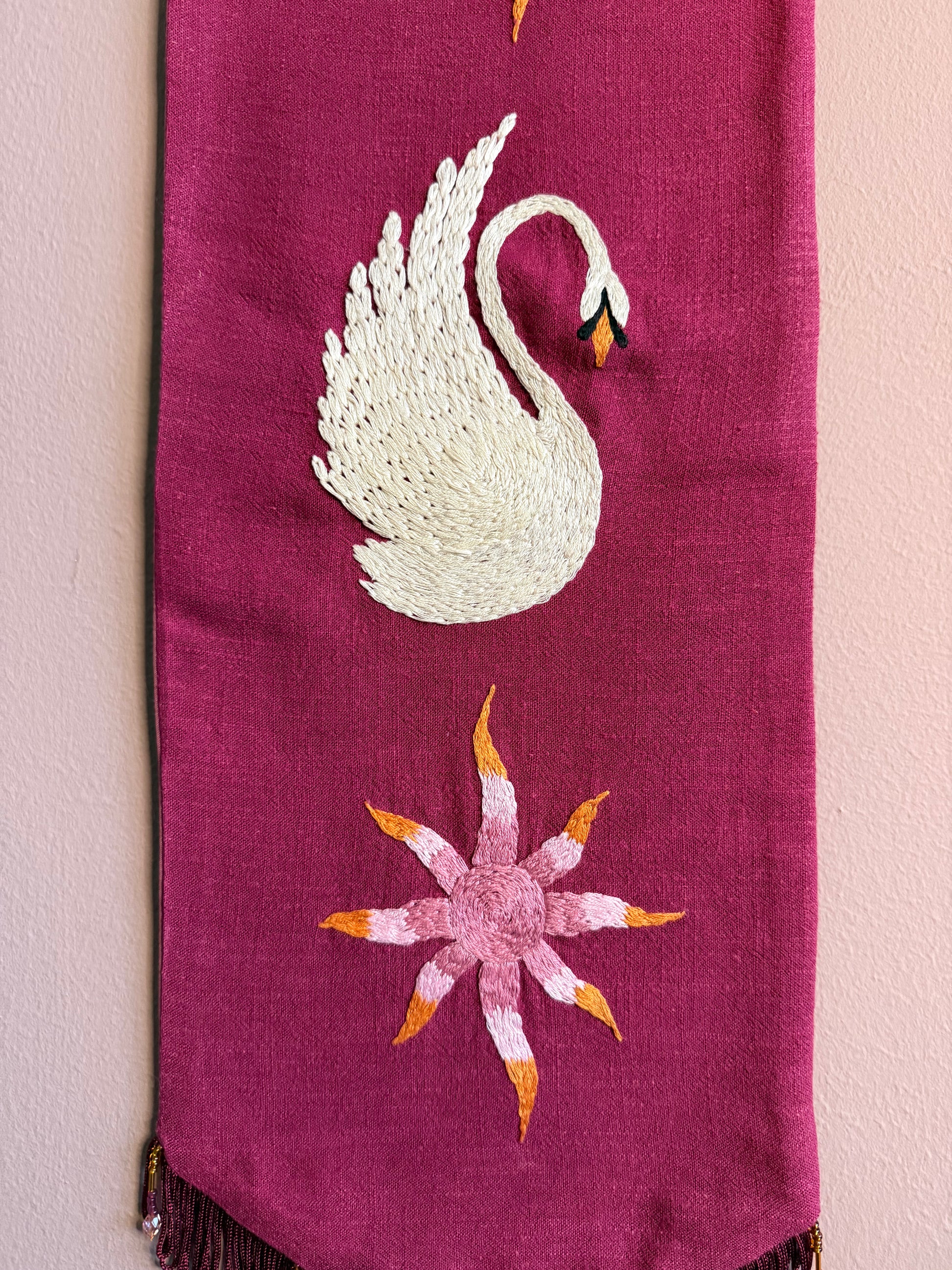 Detail van handgeborduurde wandhanger Aurora Swan met zwaanmotief, kralen en franjerand op linnen — Amber Nicola
