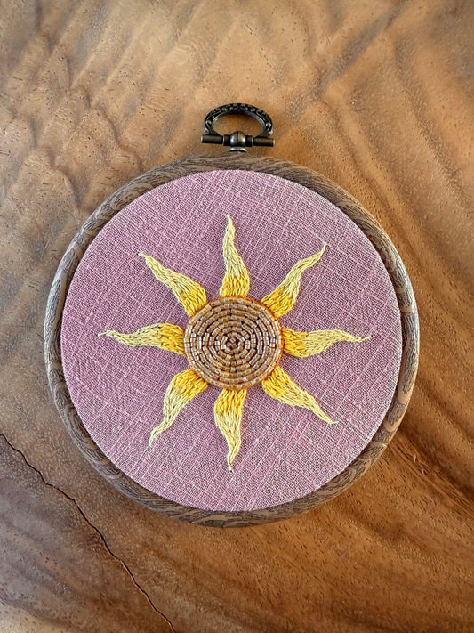 Handgeborduurde zon wandhanger op lila linnen in houtlook borduurring, gemaakt door Amber Nicola